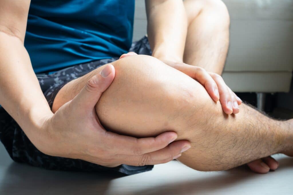 Mann hält sich schmerzendes Knie mit beiden Händen – mögliche Verletzung oder Gelenkbeschwerden